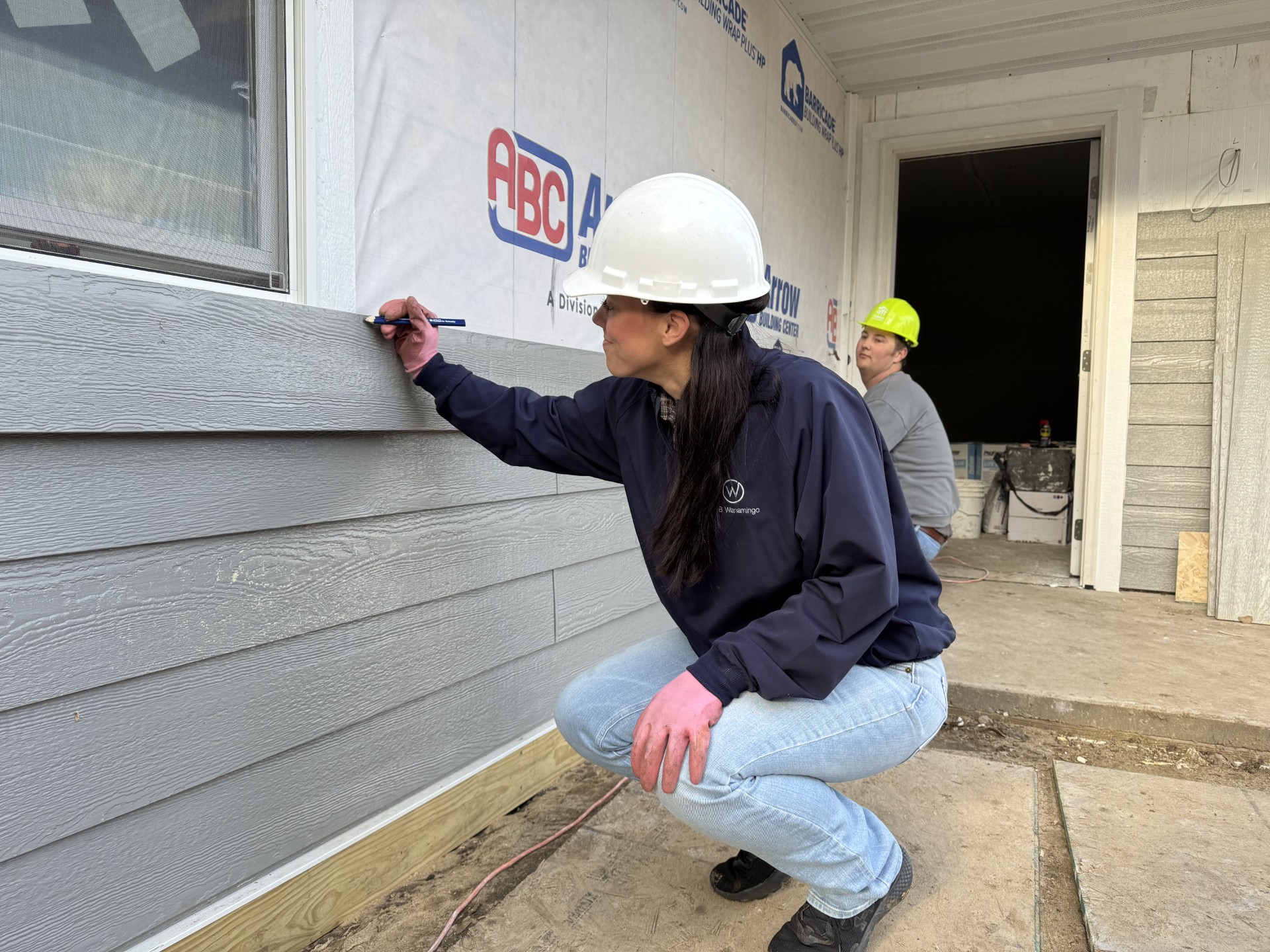 Employees installing siding on the new house